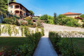 A pathway leading to a hillside property with a house, surrounded by lush greenery and flowering plants. - CASA SOFIA - MyHomeinComo (Menaggio)