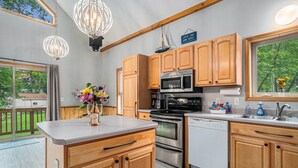 Una cocina moderna con armarios de madera, electrodomésticos de acero inoxidable y un amplio ventanal con vistas al exterior.