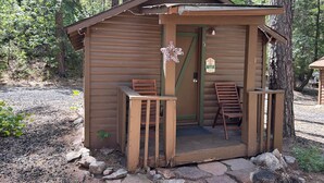 Une petite cabane en bois avec un porche, une porte et un panneau indiquant qu’il est interdit de fumer.