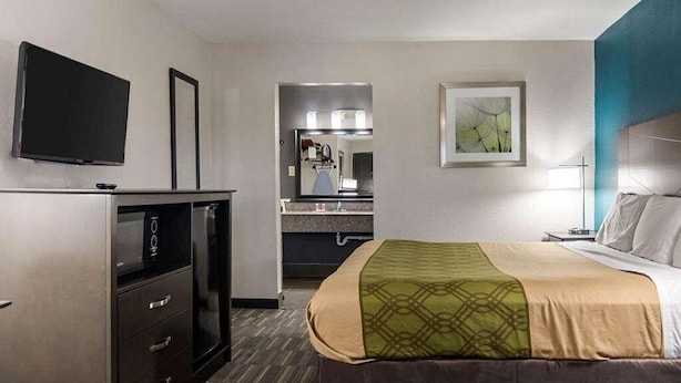 A hotel room with a bed, a TV, a desk, and a kitchenette. - HomeStay Inn & Suites (Russellville)