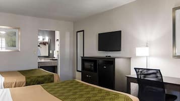 A hotel room with two beds, a desk, a television, and a mirror.