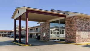 A building with a covered entrance, brick walls, and a glass door. - HomeStay Inn & Suites (Russellville)