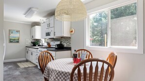 A kitchen with white cabinets, a checkered tablecloth, and a hanging light fixture.