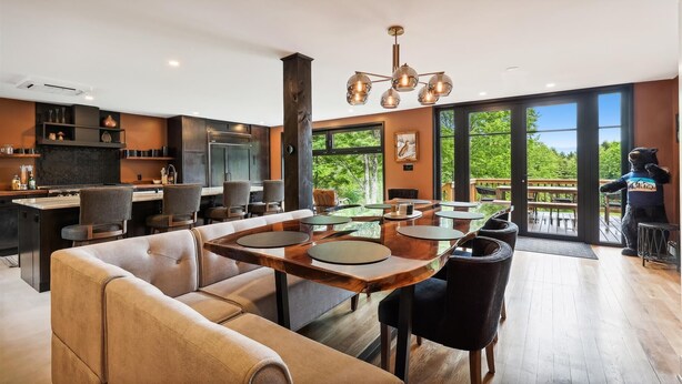 Una cocina moderna con una isla grande, comedor con mesas redondas y vistas al exterior.