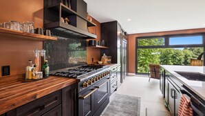 Una cocina moderna con una estufa grande, repisas de madera y vistas al exterior.