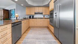A modern kitchen with wooden cabinets, stainless steel appliances, and a patterned rug. - Phenomenal Gulf Views From This Three Bedroom, Three Bathroom Condo. Complimentary Boat Slip! (Orange Beach)
