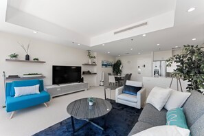 Ein modernes Wohnzimmer mit Fernseher, Sofas, einem Couchtisch und einem Essbereich.