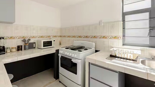 A kitchen with white cabinets, a microwave, a stove, and a sink. - Casa Ejecutiva Entera · 3 Suites Privadas · 5 min del Centro (Tlaxcala de Xicohténcatl)