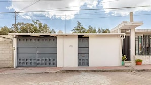 Un bâtiment doté d’une porte de garage, sur laquelle on peut lire le numéro « 2505 », et d’un petit jardin agrémenté de plantes en pot.