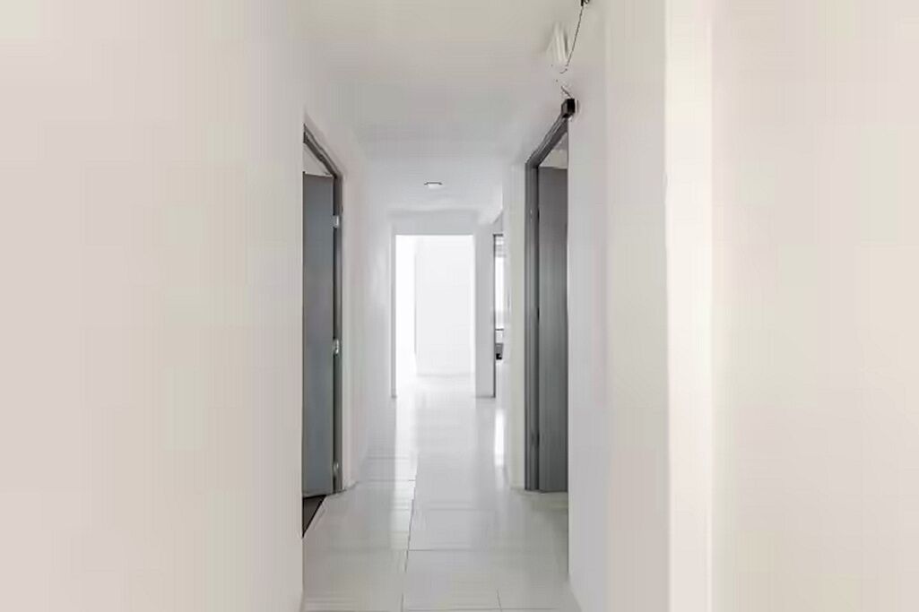 A corridor with doors on either side, leading to a bright room at the end.