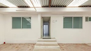 A room with a central staircase, white walls, and large windows. - Casa Ejecutiva Entera · 3 Suites Privadas · 5 min del Centro (Tlaxcala de Xicohténcatl)