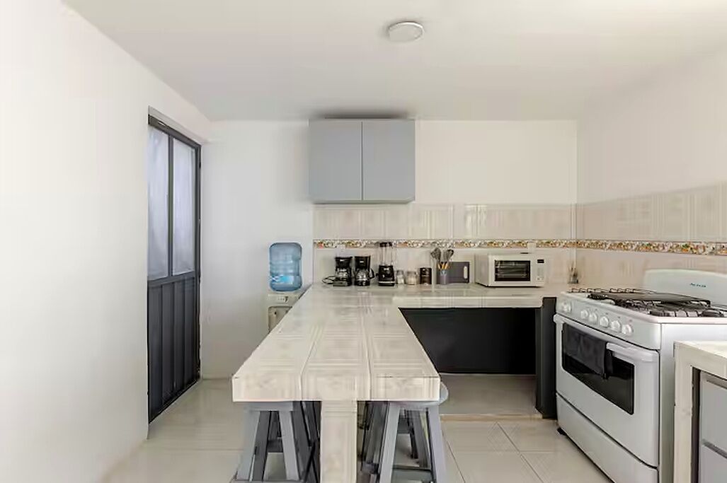 Een moderne keuken met een centraal eiland, inbouwapparatuur en een waterdispenser.