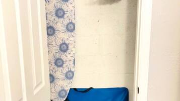 A small, enclosed space with a blue fabric item on a rack, a white door, and a wall with a subtle texture.