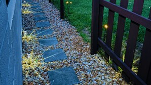 Un sentier bordé de pierres plates qui mène à une porte en bois.
