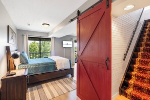 Un dormitorio con cama, mesita de noche y vistas al exterior.