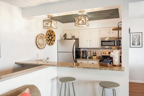 Una cocina moderna con encimeras de granito, electrodomésticos de acero inoxidable y una isla central con taburetes de bar.