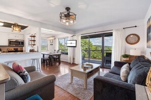 Ein modernes Wohnzimmer mit einer Couch, einem Couchtisch und einem Essbereich mit Fernseher.