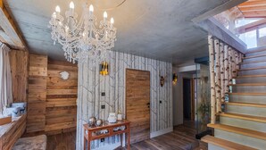 Un interior moderno con una escalera de madera, un candelabro y una pared decorada con un diseño de árbol.