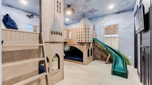 A play area with a slide, climbing structure, and a ceiling mural. - Reunion's Finest | Luxury 10BR Home w Golf Course View, Private Pool, Theater and Arcade Near Disney (Kissimmee)