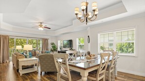A spacious living room with a dining area, hardwood floors, a ceiling fan, and large windows with blinds. - Reunite at Reunion | 3BR, 3 Bath Spacious Condo w/ Golf Course Views Near Disney (Kissimmee)