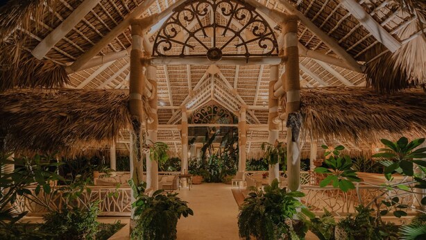 A thatched-roof structure with a central decorative element, surrounded by lush greenery and seating areas.