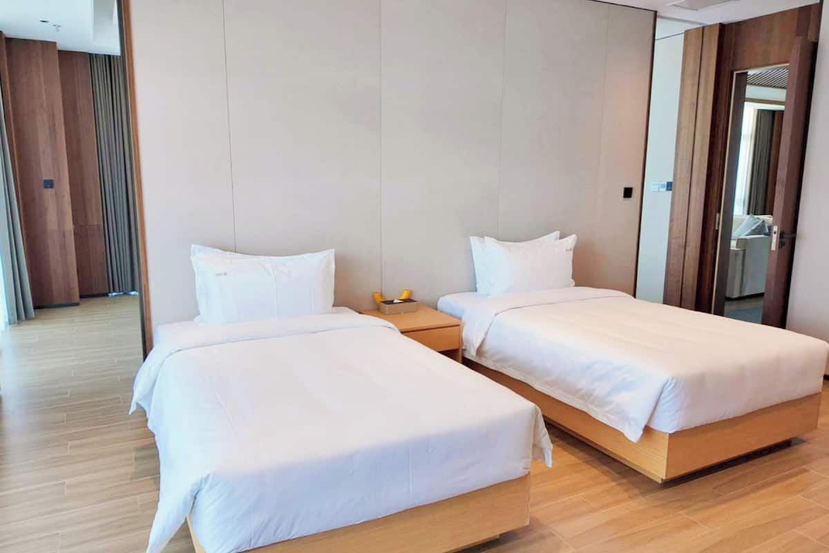 Ein Hotelzimmer mit zwei Einzelbetten, Holzboden und einer neutralen Farbgestaltung.