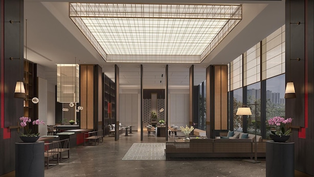 En rummelig lobby med højt til loftet, store vinduer og moderne møbler.