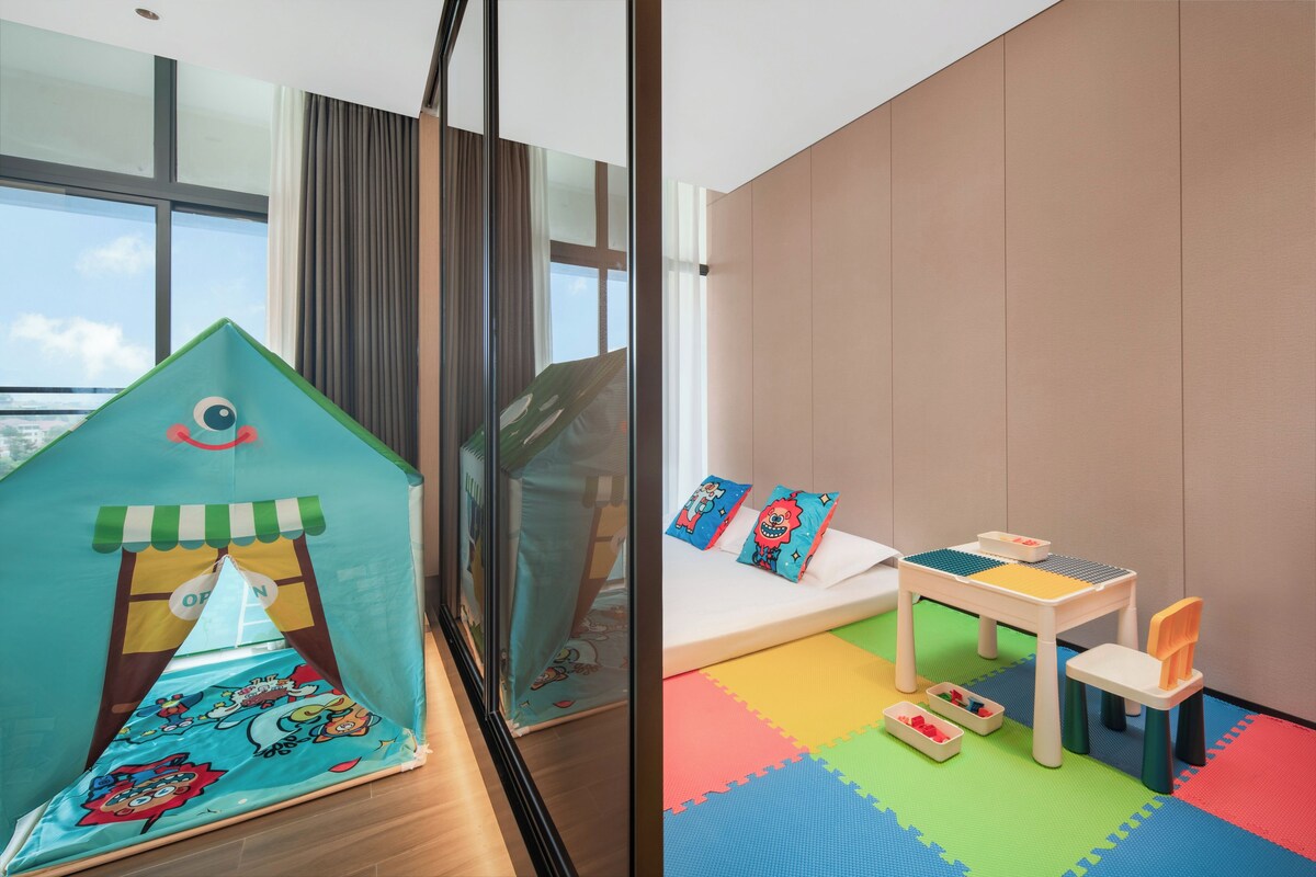 Uma área de recreação infantil com uma tenda, uma mesa pequena e tapetes coloridos.
