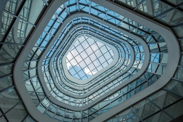 Een moderne architectuurconstructie met een centrale glazen koepel en meerdere niveaus aan balkons.