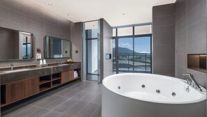 Ein modernes Badezimmer mit einer großen Badewanne, einem Doppelwaschbecken und einem großen Spiegel.