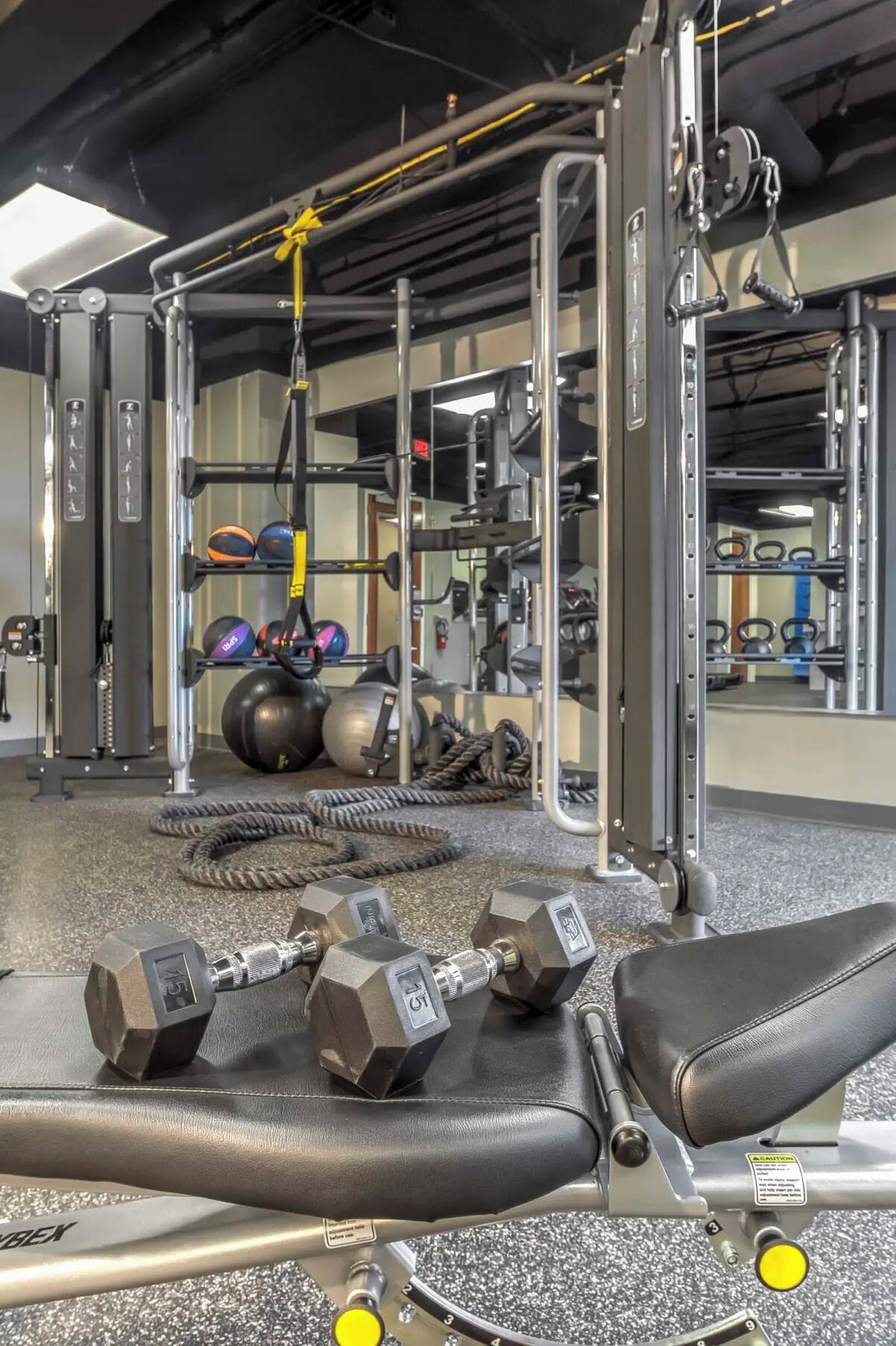 A gym with weightlifting equipment, exercise balls, and a cable machine.