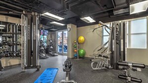 Un gimnasio con máquinas de pesas, una colchoneta azul y pelotas de ejercicio.