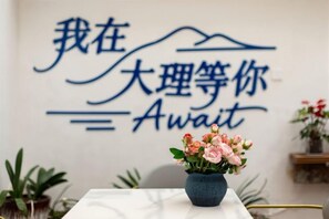 A wall with a sign in a foreign language and a vase with flowers on a table. - Waiting for You Inn (Dali City)