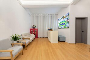 A modern living room with a wooden floor, a sofa, a red cabinet, and a blue accent chair. - Waiting for You Inn (Dali City)