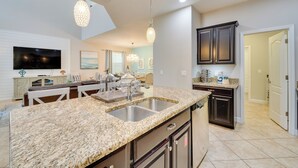 A modern kitchen with granite countertops, stainless steel appliances, and dark cabinetry.