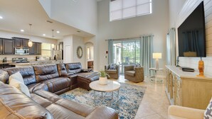 A spacious living area with a sectional sofa, a round coffee table, and a view of the kitchen and dining area.