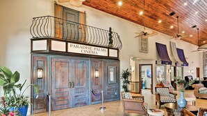 A lobby with a wooden ceiling, a balcony with a sign reading "Paradise Palms Cinema," and a seating area with various chairs and tables.
