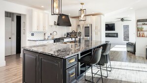 Een moderne keuken met een groot eiland, witte kastjes en zwarte accenten.