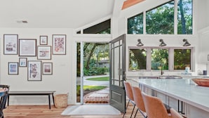 A modern kitchen with a large island, bar seating, and a view of the outdoors. - Upscale Coastal Ranch ~ Private Pool & Spa ~ 13 Planters Wood Ct ~ Sleeps 10 (Hilton Head Island)