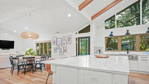 A spacious kitchen with a large island, wooden flooring, and a dining area with chairs and a table. - Upscale Coastal Ranch ~ Private Pool & Spa ~ 13 Planters Wood Ct ~ Sleeps 10 (Hilton Head Island)