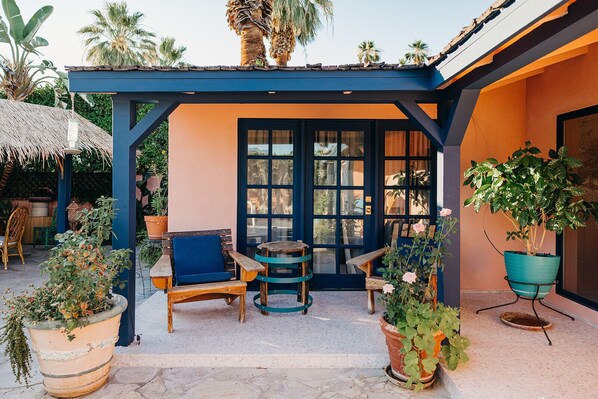 An outdoor seating area with a blue pergola, wooden chairs, and potted plants.