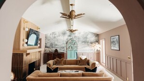 A living room with a sofa, a fireplace, and a wall with a mural.
