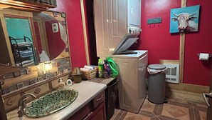 Una cocina compacta con un lavamanos, armarios, un microondas y un cubo de basura.