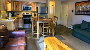 Una cocina moderna con armarios de madera, electrodomésticos de acero inoxidable y una zona de comedor con mesa y sillas de madera.