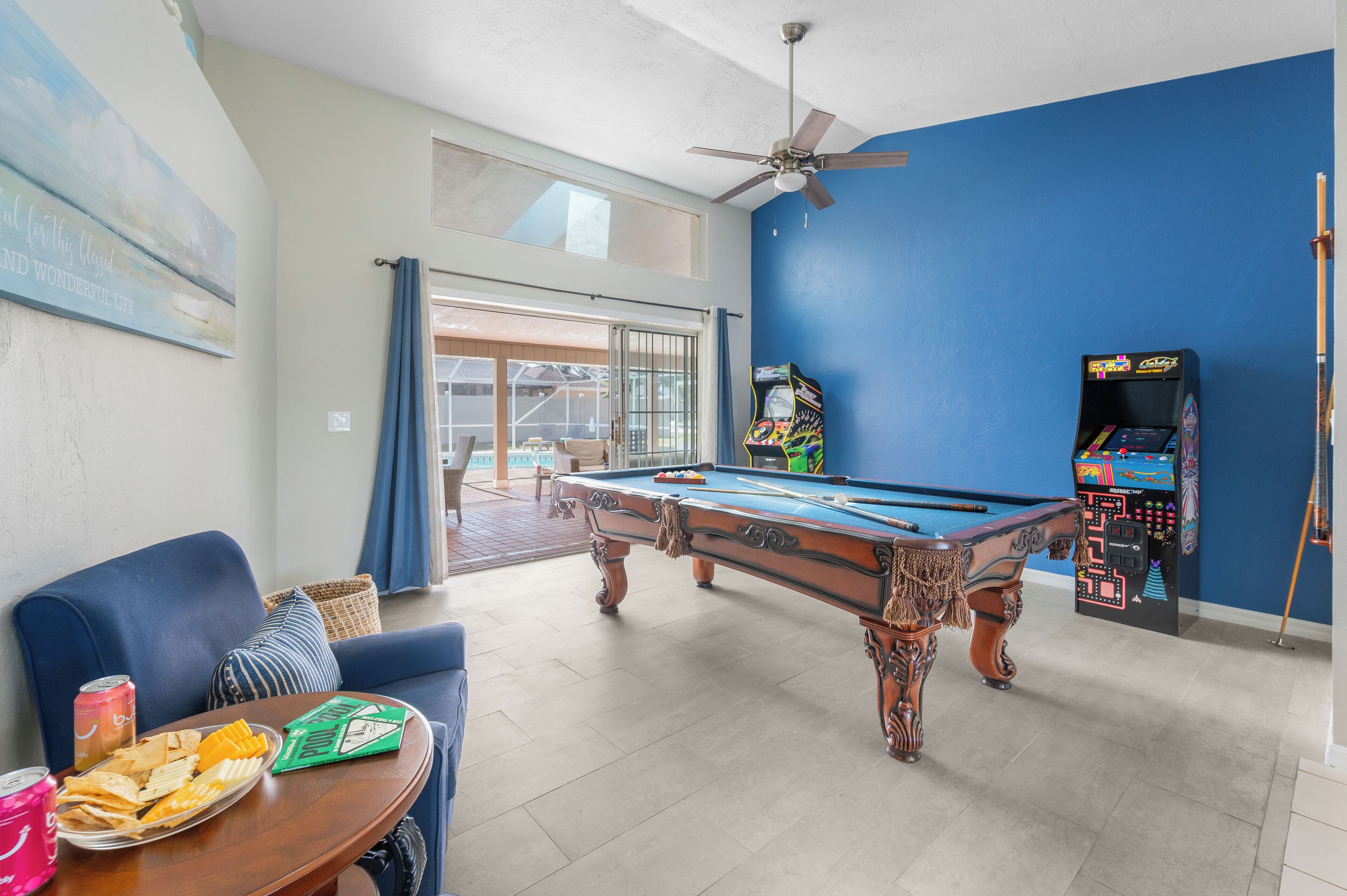 A pool table in a room with a blue wall, a ceiling fan, and a pool table with balls.