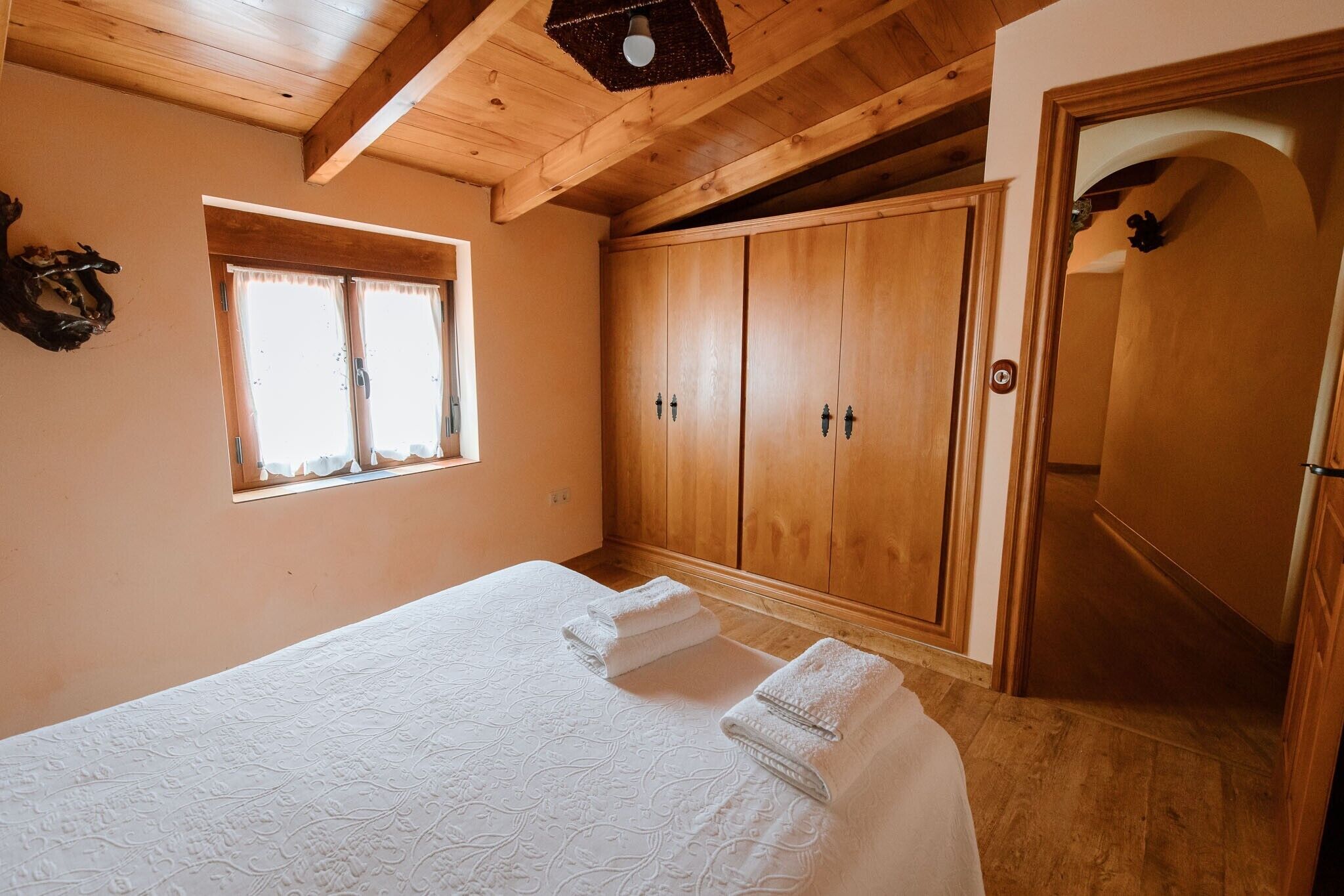 Un dormitorio con una cama, un armario de madera y una ventana.