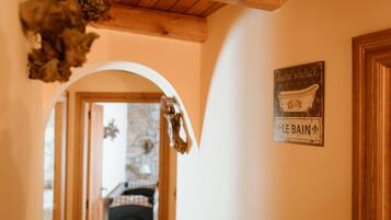 Un pasillo con techo de madera, un letrero que dice 'Carte Postale Le Bain' y un vano que da a otra habitación.