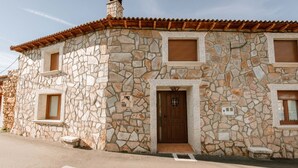 Un edificio de piedra con techo de tejas, una puerta de madera y un pequeño porche.