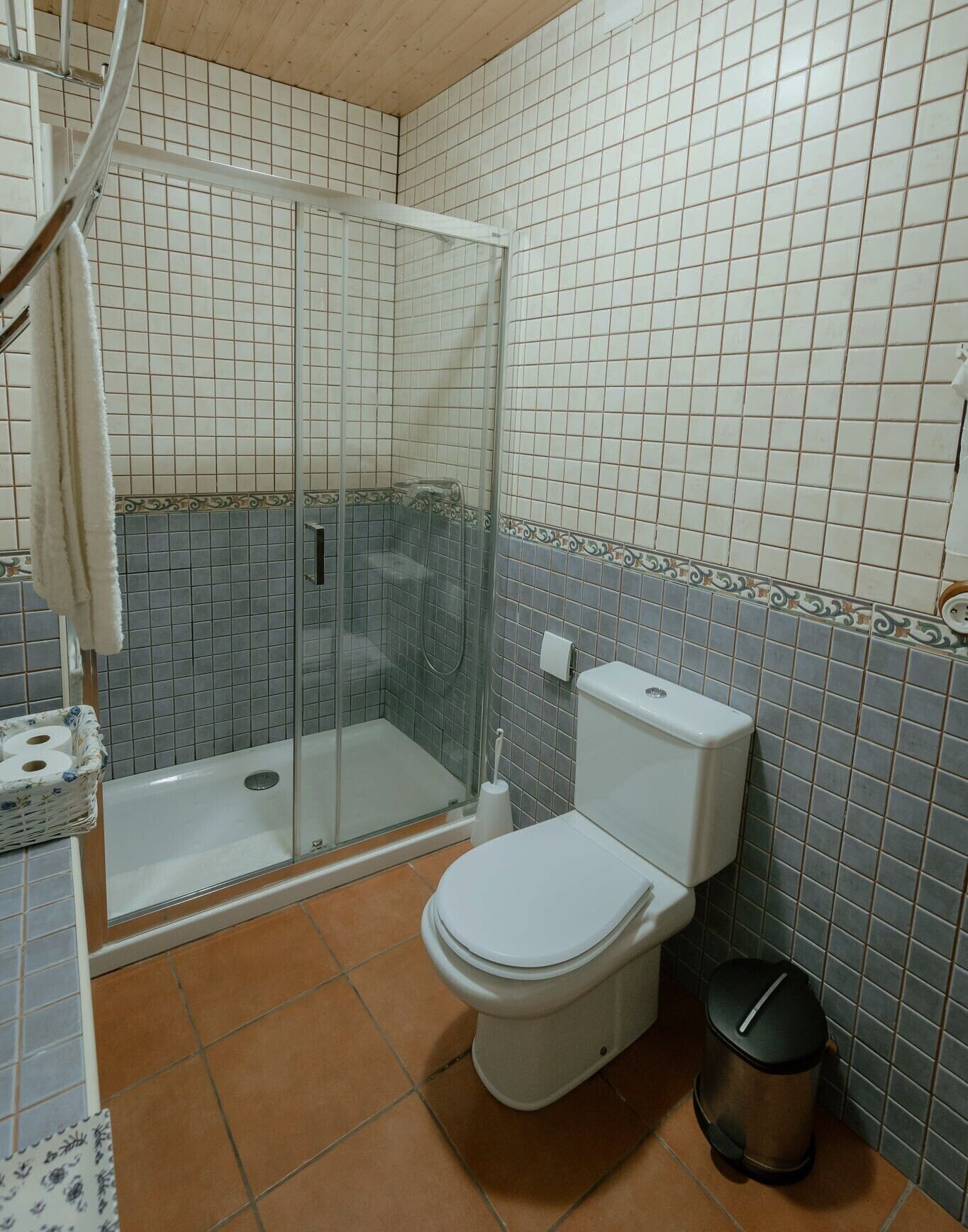 Un baño con cabina de ducha de vidrio, inodoro y cubo de basura.