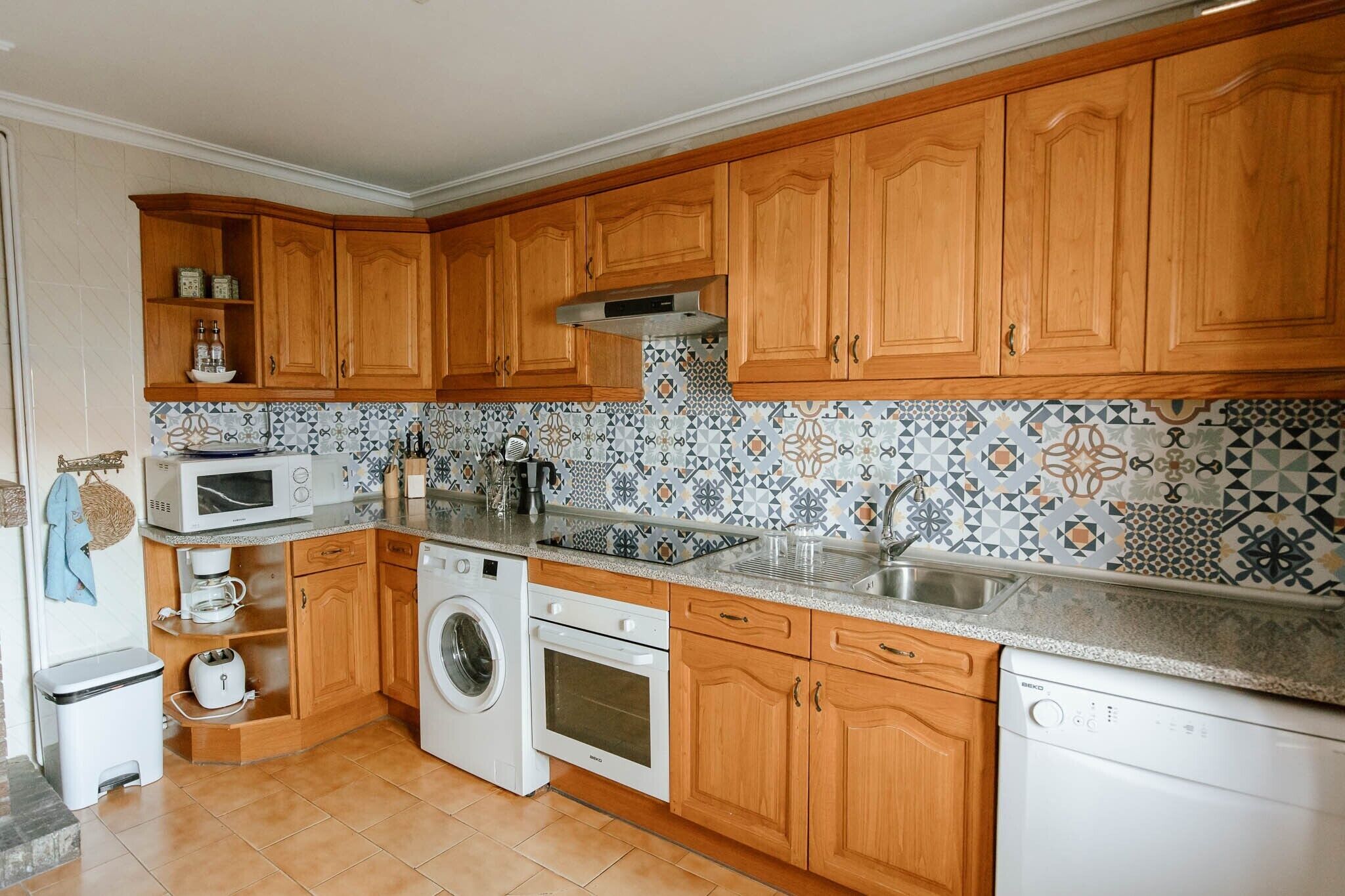Une cuisine avec des meubles en bois, un lave-linge, un four à micro-ondes et un lave-vaisselle.